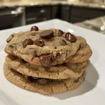 Juicy and inviting chocolate chip cookie, featuring semi-sweet chocolate chips and a light golden color.