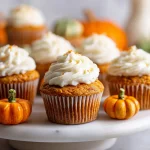 Close-up of freshly baked pumpkin cupcakes topped with cream cheese frosting and a sprinkle of cinnamon.