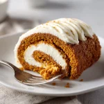 Close-up of a pumpkin roll filled with brown butter cream cheese, showcasing its texture and spiral design.