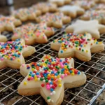 A selection of soft cut-out sugar cookies with a glossy icing finish and vibrant sprinkles, captured in detail.