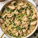 High protein chicken orzo dish in a white pan with spinach, asparagus and parmesan.