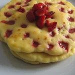Stack of strawberry pancakes on a blue plate.