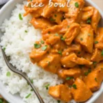 Overhead shot of coconut chicken rice bowl with parsley garnish and antique fork.