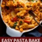 Close-up of a veggie pasta bake in a white casserole dish with a serving spoon.