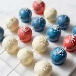 A colorful display of six 4th of July cake pops decorated with red, white, and blue icing and sprinkles.