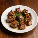 Close-up of garlic butter steak bites cooked in an air fryer, garnished with fresh parsley.