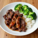 A plate of crispy air fryer beef and broccoli served with a savory sauce.