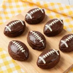Close-up of fudgy football-shaped brownies on a wooden table.