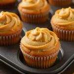Close-up of pumpkin cream cheese swirl muffins on a wooden table.