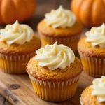 Close-up of swirled pumpkin cream cheese muffins on a wooden table.