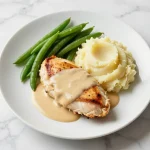 A delicious creamy garlic chicken served with rich gravy and fluffy mashed potatoes